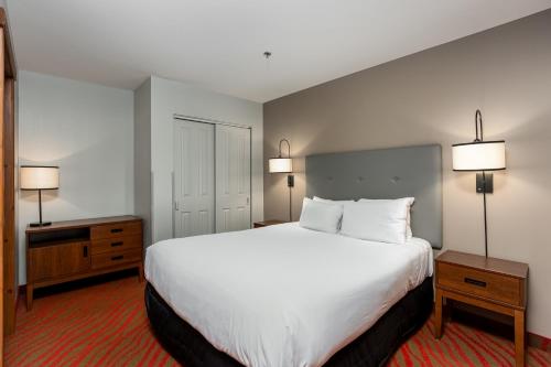 a bedroom with a large white bed and two lamps at La Tour des Voyageurs II in Mont-Tremblant