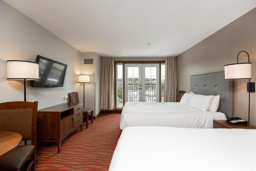 a hotel room with two beds and a desk at La Tour des Voyageurs II in Mont-Tremblant