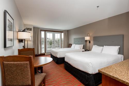 a hotel room with two beds and a table at La Tour des Voyageurs II in Mont-Tremblant
