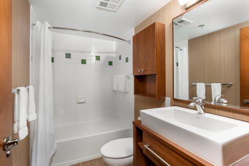 a bathroom with a sink and a toilet and a mirror at La Tour des Voyageurs II in Mont-Tremblant