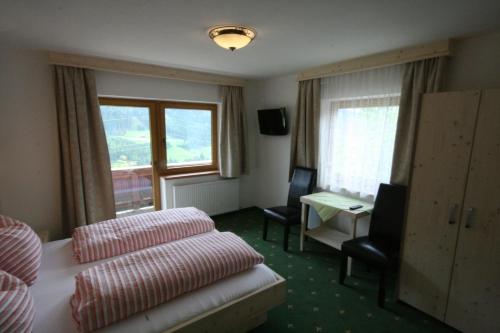 ゲルロスベルクにある"Adamerhof"のベッド、デスク、窓が備わるホテルルームです。