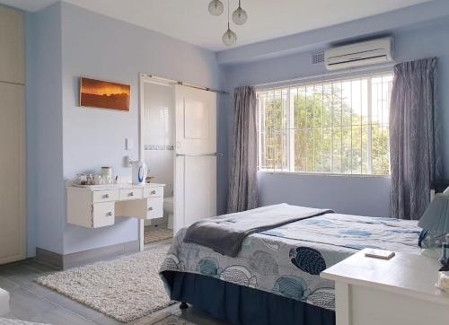1 dormitorio con cama, lavabo y ventana en Whalehaven, en Southbroom