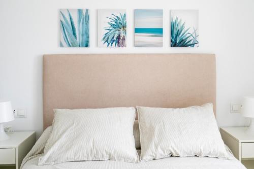 ein Schlafzimmer mit einem Bett mit vier Bildern an der Wand in der Unterkunft Montevideo Beach - Apartamento con vistas al mar recién renovado in Algarrobo-Costa