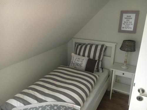 a small bedroom with a bed and a lamp at Lykkehus in Humptrup