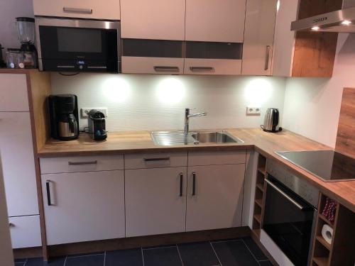 a kitchen with white cabinets and a sink at Lykkehus in Humptrup