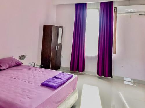een slaapkamer met een paars bed en paarse gordijnen bij Tiara Guest House Mitra RedDoorz in Samarinda