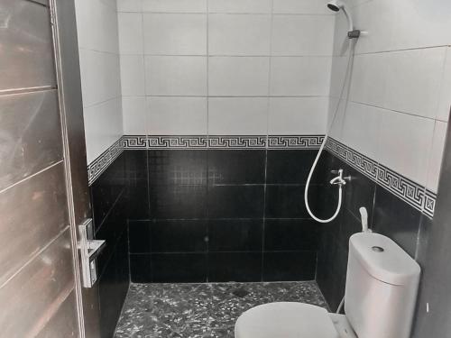 een kleine badkamer met een toilet en een douche bij Tiara Guest House Mitra RedDoorz in Samarinda