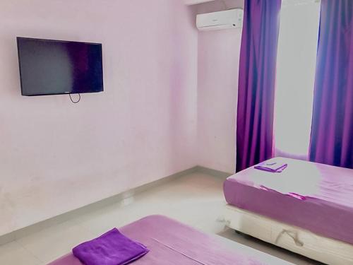 een kamer met een bed en een tv aan de muur bij Tiara Guest House Mitra RedDoorz in Samarinda
