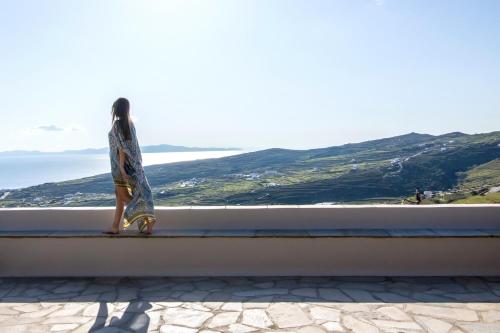 a woman standing on a ledge looking out at the ocean at Villa Adele in Arnados
