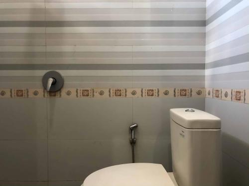 a bathroom with a toilet and a striped wall at RedDoorz at Daffi Araya in Malang