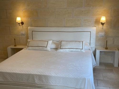 a bedroom with a white bed with two pillows at MAREULIVI in Ostuni