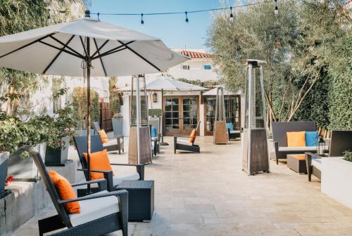 an outdoor patio with chairs and an umbrella at Hotel Marisol Coronado in San Diego