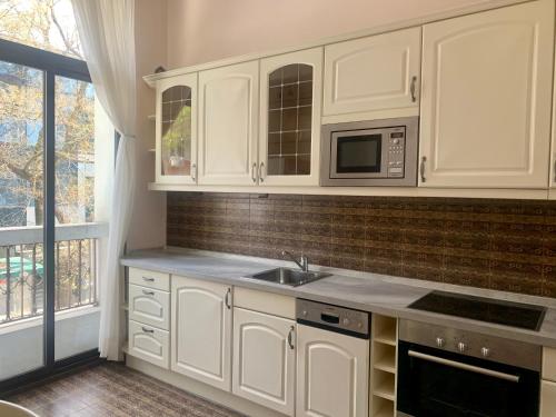 a kitchen with white cabinets and a sink and a microwave at Tsar Simeon Veliki in Stara Zagora
