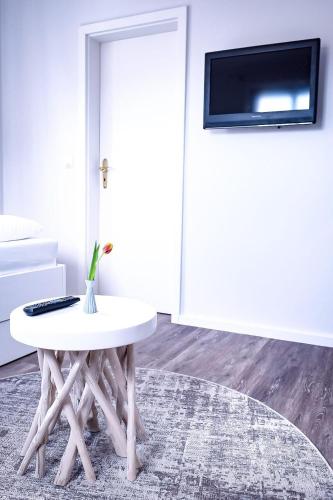 Habitación con mesa blanca y TV en la pared. en Flippi-s-Hues-NORD en Westerland