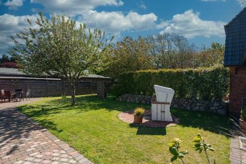 un jardín con una silla y un árbol en Flippi-s-Hues-NORD en Westerland