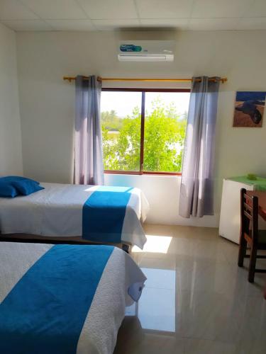 a bedroom with two beds and a window at Hostal Los Flamencos in Puerto Villamil