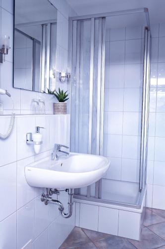 a white bathroom with a sink and a shower at Flippi-s-Hues-SUeD in Westerland (Sylt)
