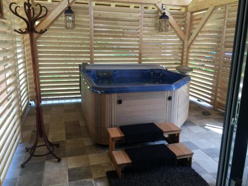 Una gran bañera azul en una habitación con paredes de madera. en Gite bien-être hammam et jacuzzi ,sauna en La Grotte