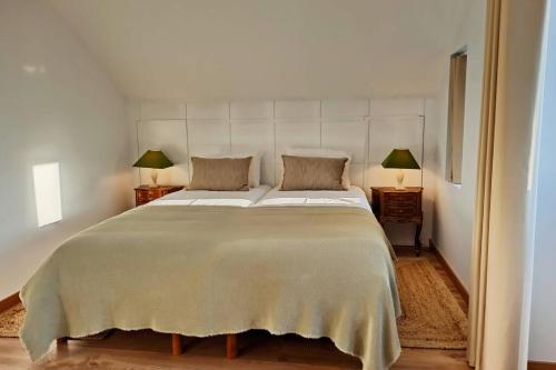 a bedroom with a large bed with two lamps on tables at Villa Tauria- Casa de campo em aldeia medieval in Sabugal