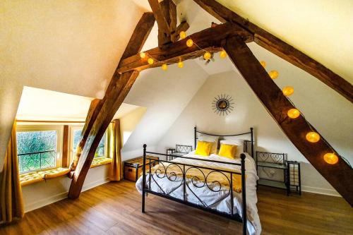 ein Schlafzimmer im Dachgeschoss mit einem Bett mit gelben Kissen in der Unterkunft Maison normande au bord de Seine, Le Verger de Pacôme in Anneville-Ambourville