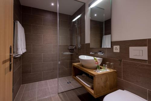 W łazience znajduje się umywalka i przeszklony prysznic. w obiekcie Pradas Resort Brigels w mieście Breil/Brigels