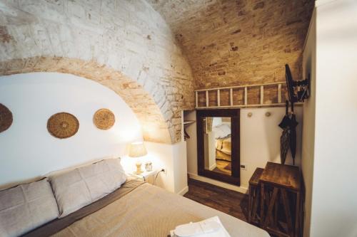 1 dormitorio con cama y pared de piedra en Trullo Syrah-Trulli Antì Charme & Relax en Alberobello