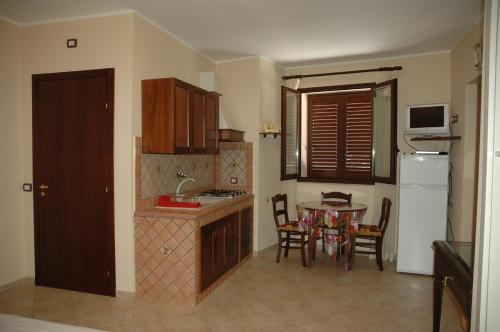 a kitchen with a table and chairs and a refrigerator at Puesta De Sol Residence in Lampedusa