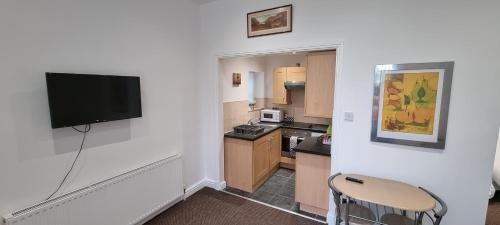 a small kitchen with a flat screen tv on a wall at No 7 - 1 BED NEAR SEFTON PARK AND LARK LANE in Liverpool