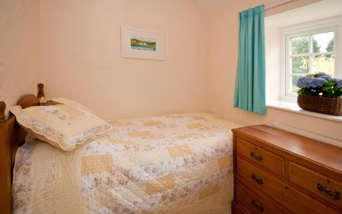 a bedroom with a bed with a dresser and a window at Tros Yr Afon Holiday Cottages and Manor House in Beaumaris