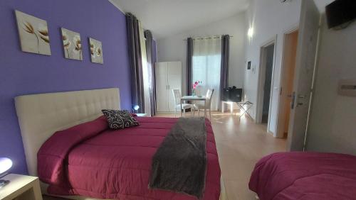 um quarto com paredes roxas, uma cama e uma mesa em La Suite Di Segesta em Calatafimi