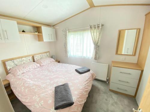 een slaapkamer met een roze bed en een spiegel bij Waggy Tails - Hot Tub - Pet Friendly in South Cerney