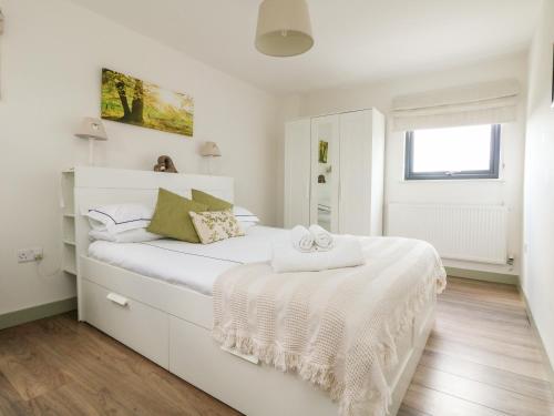 a white bedroom with a white bed and a window at Oakwood in Par