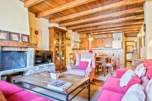 a living room with pink furniture and a fireplace at Baqueira Apartamentos Cota 1700 a pie de pistas in Baqueira-Beret