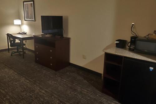 a hotel room with a desk and a television at Cobblestone Suites - Oshkosh in Oshkosh