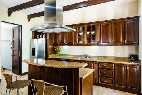 a kitchen with wooden cabinets and a stainless steel refrigerator at Dream House in prestigious Hacienda Pinilla in Tamarindo
