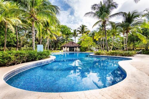 a swimming pool with palm trees and a gazebo at Dream House in prestigious Hacienda Pinilla in Tamarindo