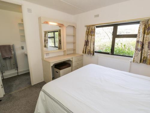 a bedroom with a bed and a desk and a mirror at Springtime Lodge in Llanddulas