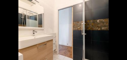 La salle de bains est pourvue d'un lavabo et d'une porte de douche en verre. dans l'établissement Vieux-port, Panier, magnifique studio avec vue sur mer, à Marseille