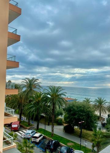 a view of a parking lot with palm trees and the ocean at Hotel Alba Chiara in Finale Ligure