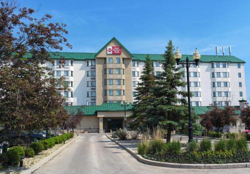 a large building with a green roof on a street at Best Western Plus Winnipeg Airport Hotel in Winnipeg