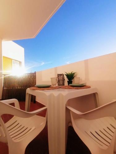 a white table with two chairs and a table with a plant on it at Lovely apartment 500 m walk to the beach in Portimão