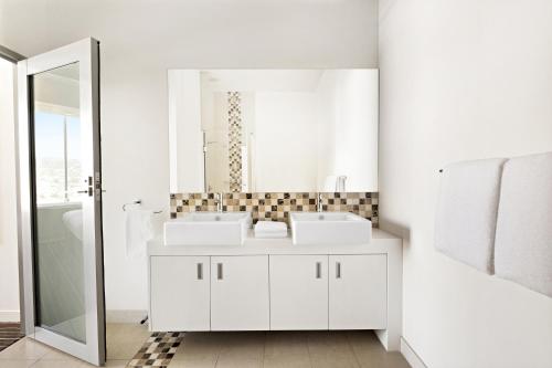 a white bathroom with two sinks and a mirror at Mantra Charles Hotel in Launceston