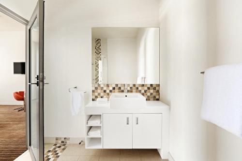 a white bathroom with a sink and a mirror at Mantra Charles Hotel in Launceston
