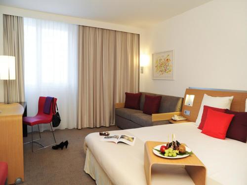 ニュルンベルクにあるノボテル ニュルンベルク アム メッセツェントルムのベッドとソファ付きのホテルルーム