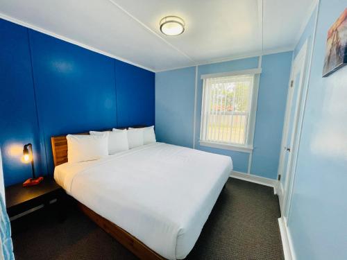a blue bedroom with a large white bed with a window at The Anchorage Motel in Pacific City