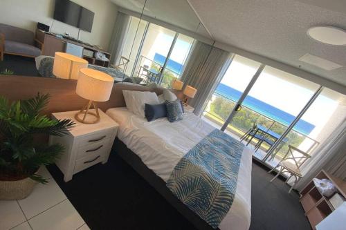 a bedroom with a bed with a view of the ocean at Ocean Bliss - Top floor beachfront studio with amazing views ! in Marcoola