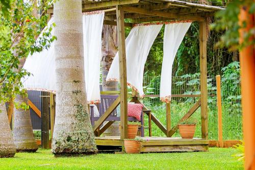 a wooden gazebo in a yard with two trees at Pousada Bernúncia in Penha