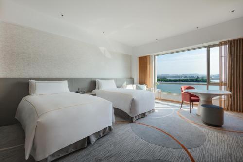 two beds in a room with a large window at InterContinental Suzhou Hotel by IHG in Suzhou