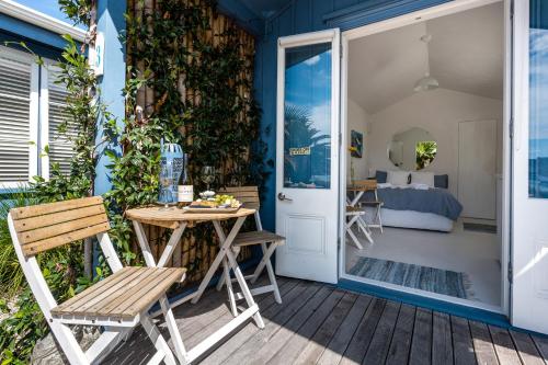 a patio with a table and chairs on a deck at Boatsheds on the Bay, Waiheke Island in Ostend