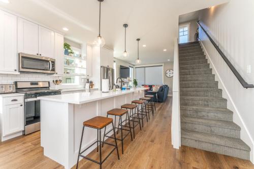 a kitchen with white cabinets and a bar with stools at Shore Beats Work #100 in Chelan